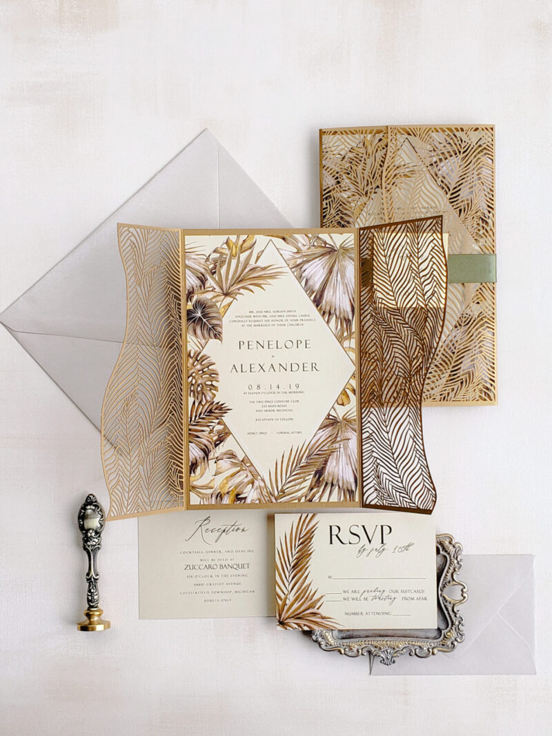 Luxury tropical laser cut wedding invitations featuring an intricate gold gate fold design with a tropical motif, perfect for destination weddings.