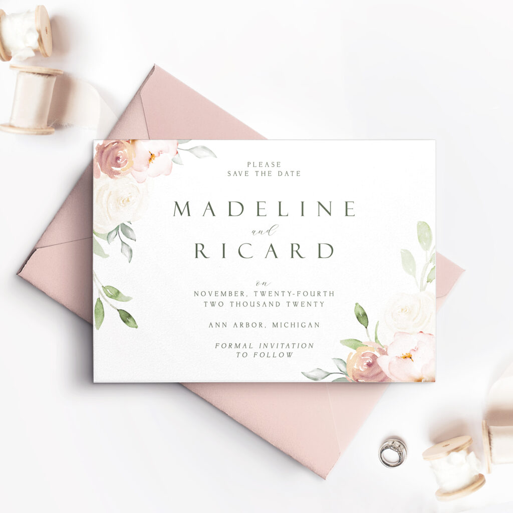 pink envelope with white save the date card and pink roses with leaves