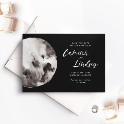 black save the date card with white envelope and moon design