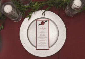 Red, black, and white layered wedding menu card with wax seal and ribbon finish