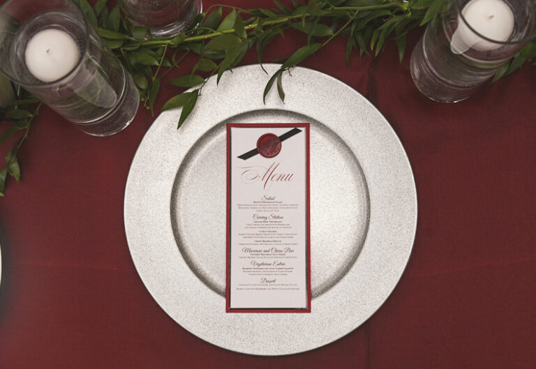 Red, black, and white layered wedding menu card with wax seal and ribbon finish