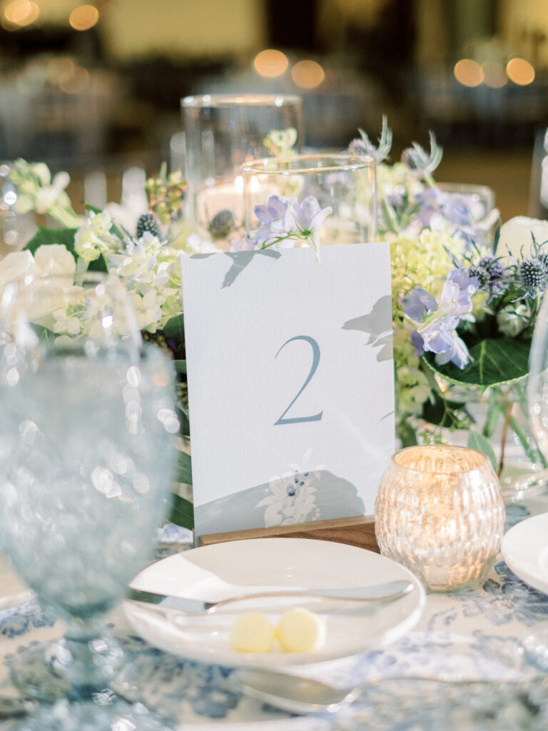 Wedding day stationery setup with menus, place cards, table numbers, and signage displayed on a reception table.