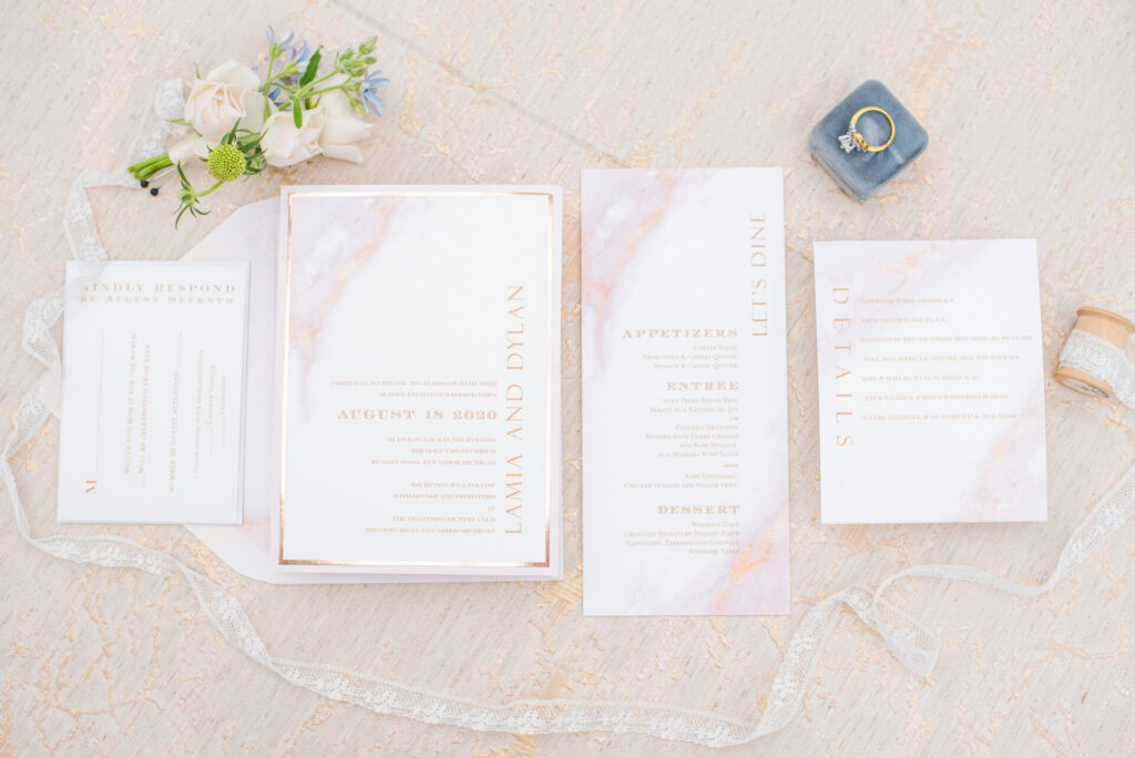 Flat lay of wedding invitation suite showing RSVP, details card, and envelope liner