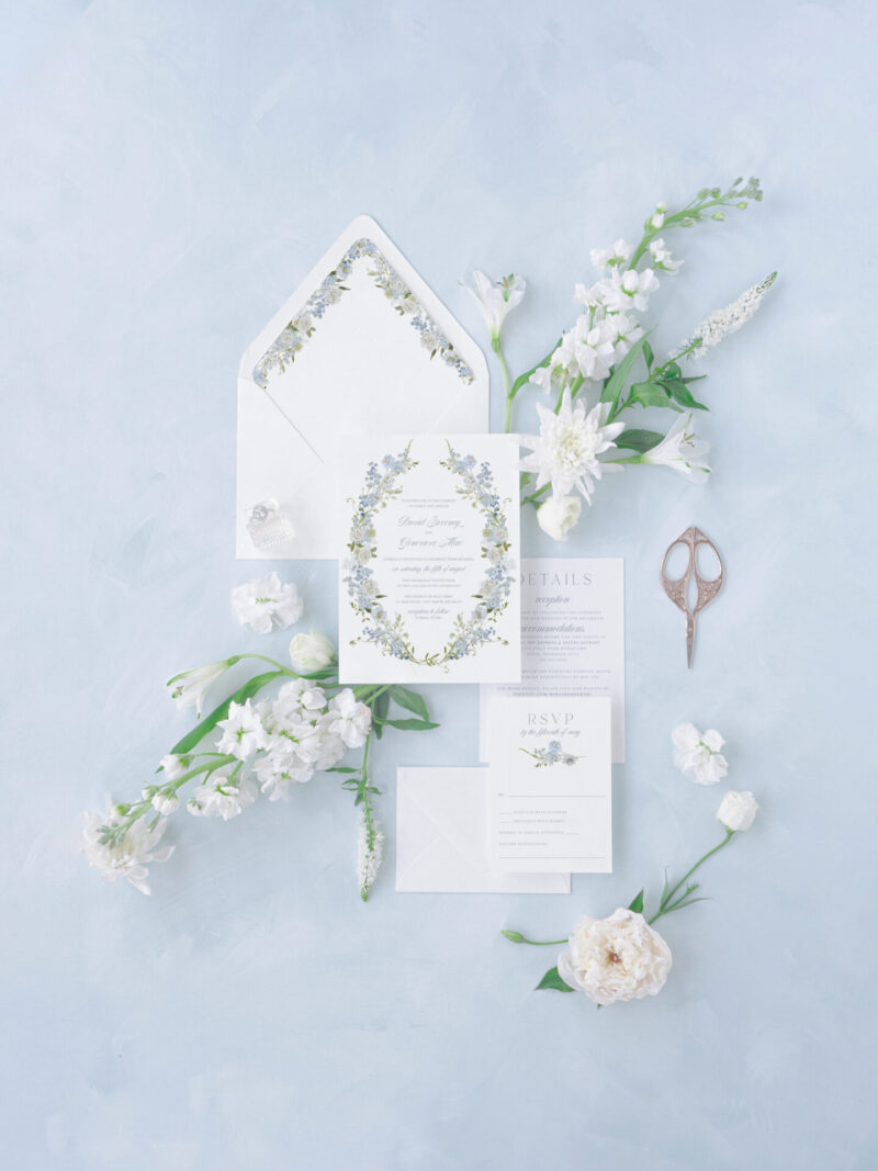 Garden-inspired wedding invitations with delicate blue florals and a romantic wreath frame, perfect for spring or outdoor weddings.