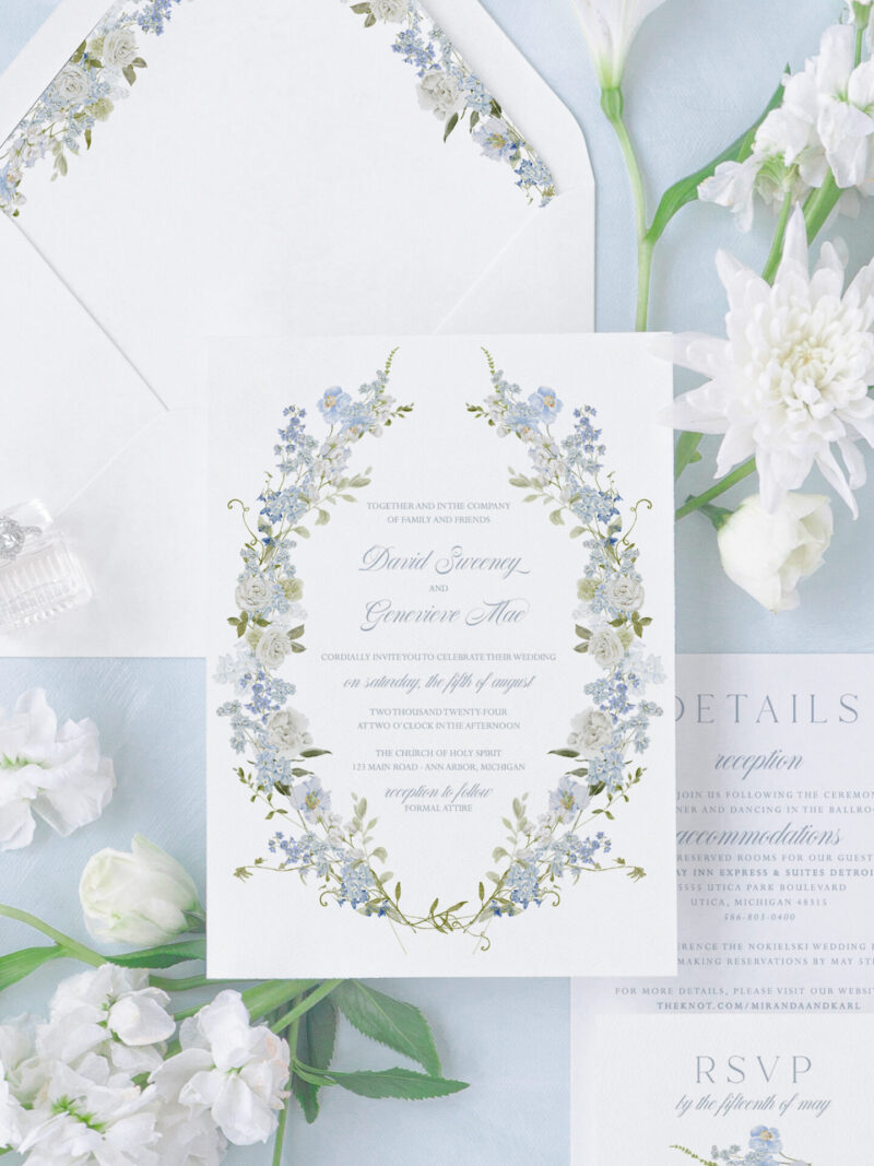 Blue floral wedding invitation suite with romantic wreath design, matching RSVP card, details card, and floral envelope liner.