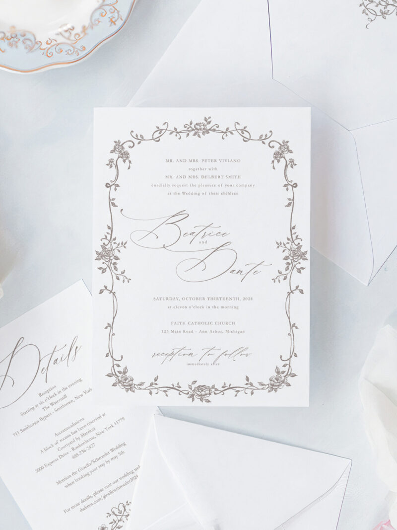 Romantic script wedding invitations with an elegant floral frame, matching RSVP card, details card, and floral envelope liner.