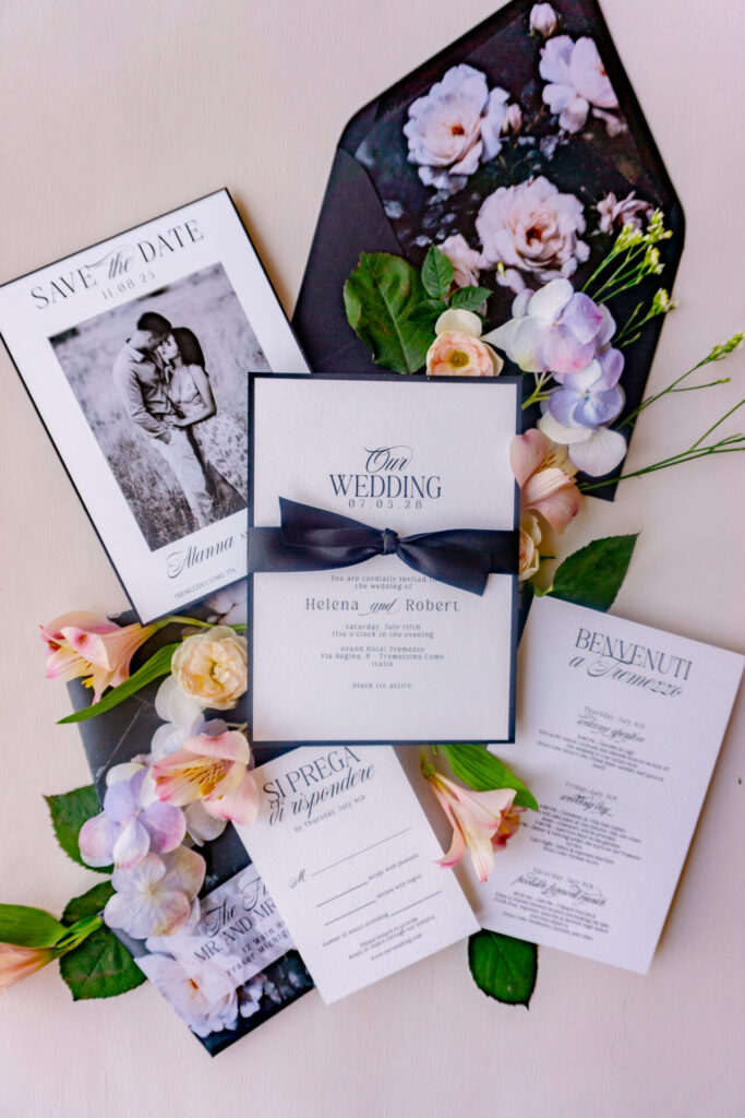 Black and white wedding invitation suite flatlay with floral envelope liner, satin ribbon, and elegant typography for Lake Como wedding